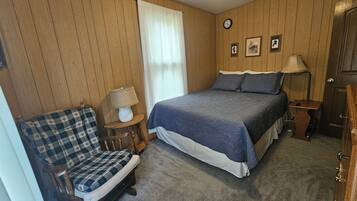 A bedroom with a bed, a chair, a lamp, and a clock on the wall.