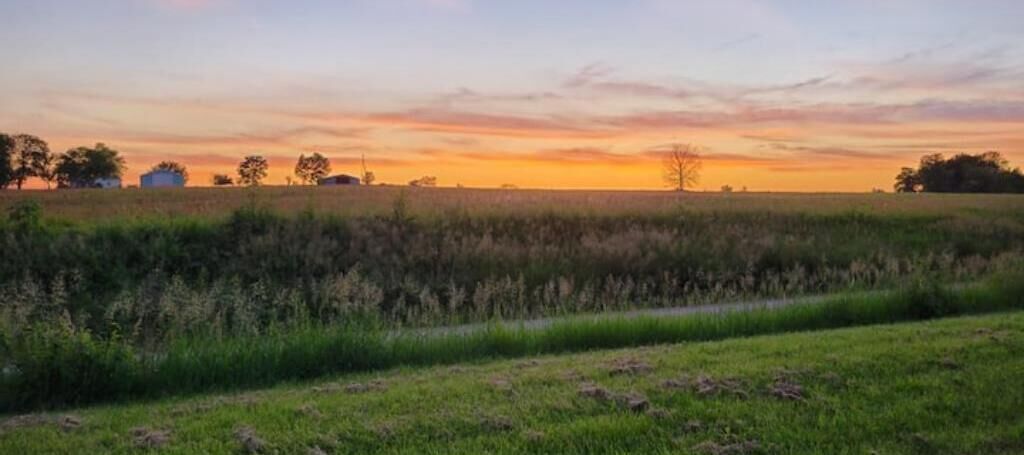 A wide-open field with a sunset in the background.