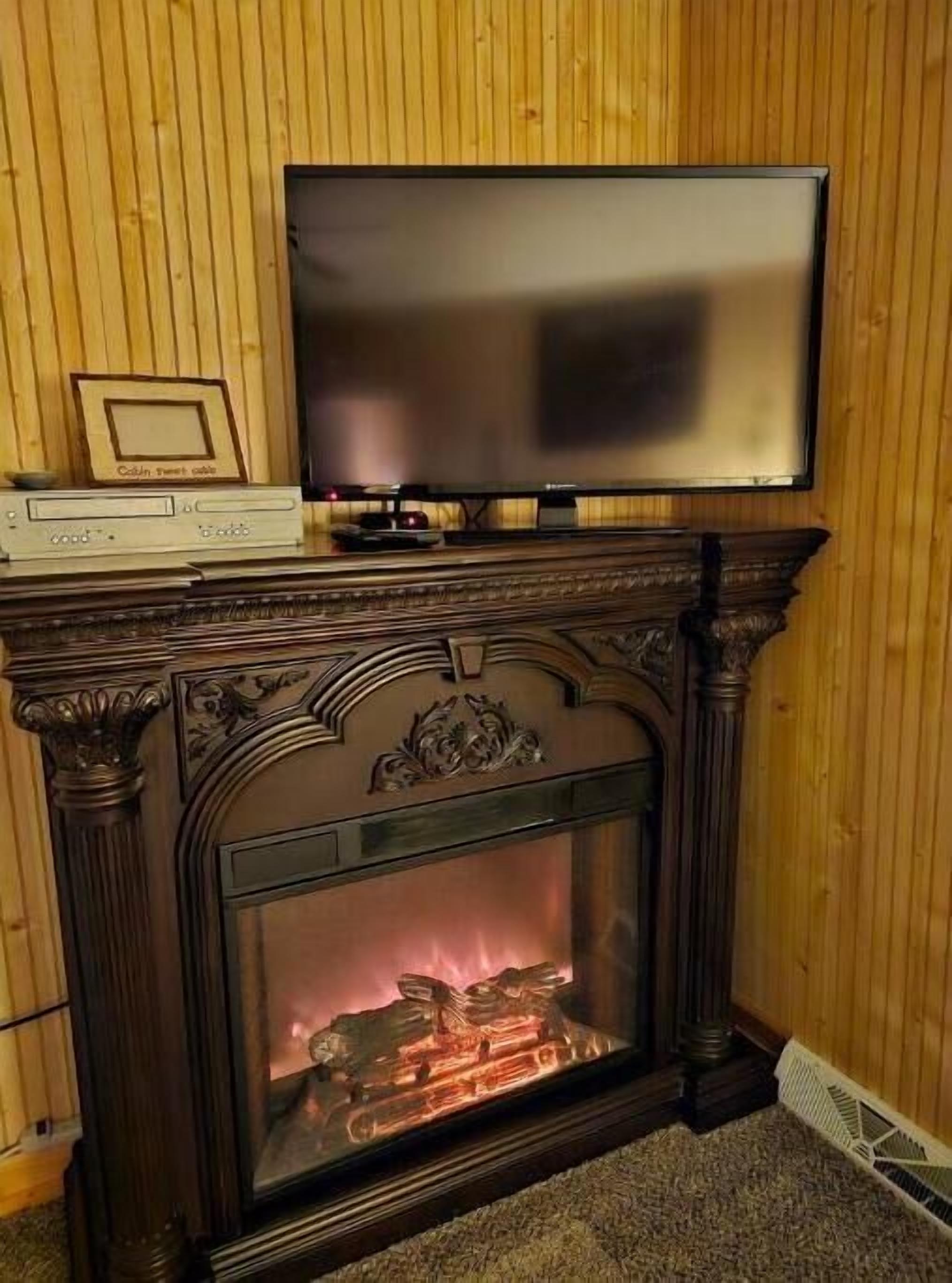 Takka, jonka päällä on televisio, kehystetty kuva ja koristeellinen takanreunus.