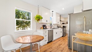 A modern kitchen with white cabinetry, a stainless steel refrigerator, and a wooden dining table. - Hickory House - Family/Group and Pet-Friendly Retreat Near Lockhart Square! (Lockhart)