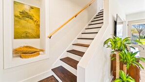 A staircase with wooden steps and a handrail, a framed artwork on the wall, and a basket on the lower landing. - Hickory House - Family/Group and Pet-Friendly Retreat Near Lockhart Square! (Lockhart)