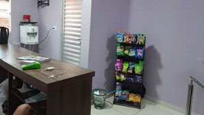 A room with a desk, a water dispenser, a vending machine, and a trash bin. - ITIS HOTEL (Dom Eliseu)