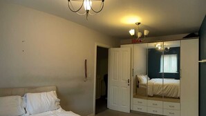 Un dormitorio con cama, armario y espejo.