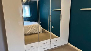 Un dormitorio con un armario grande, una cama y una ventana con persianas.