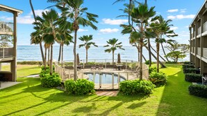 A pool area with palm trees, a deck, and a view of the ocean. - 3 Bedroom Ocean Front Condo with Pool & Elevator! (Kapaʻa)