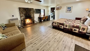 A cozy living room with a fireplace, a dining area, and a kitchenette.