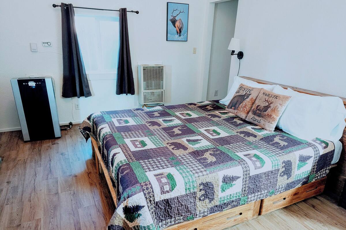 Une chambre à coucher avec un lit en bois, une courtepointe, un radiateur et une fenêtre avec des rideaux.