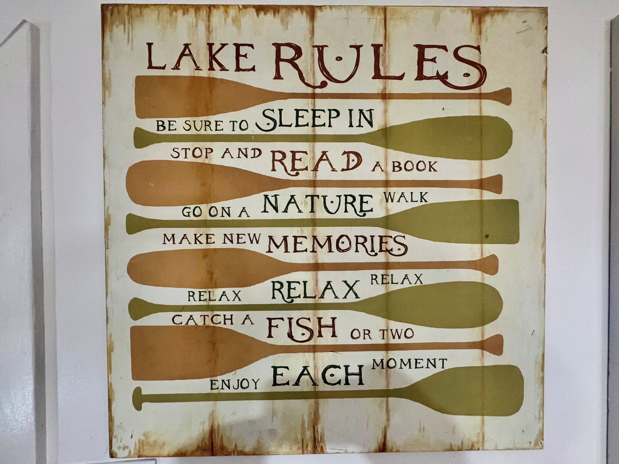 Un cartel con la leyenda 'LAKE RULES' y diversas actividades como leer, paseos por la naturaleza y relajarse.