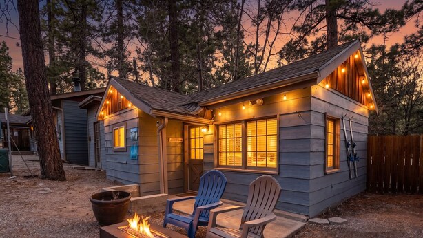 A cabin with a fire pit, two Adirondack chairs, and a deck.