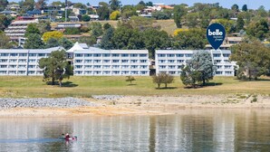 A hotel with multiple floors, a large building with a flat roof, and a sign reading "belle property escapes". - Horizons 404 (Jindabyne)