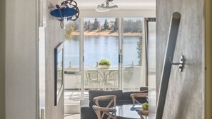 A room with a view of a lake, a dining area with a table and chairs, and a large window.