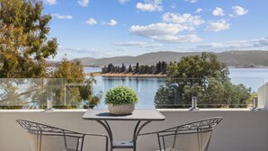 A balcony with a table and chairs overlooking a lake, surrounded by trees and hills. - Horizons 404 (Jindabyne)