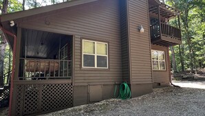 Une cabane de plain-pied dotée d’un porche couvert, d’un petit balcon et d’une allée gravillonnée.