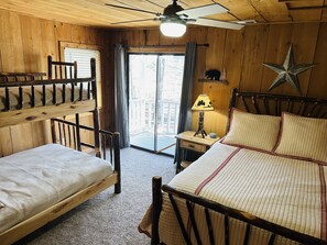 Ein Holzhütten-Zimmer mit einem Etagenbett, einem Einzelbett, einem Nachttisch mit Lampe und einer Stern-Dekoration an der Wand.