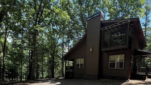Une cabane à deux étages avec une allée en gravier et un porche couvert.
