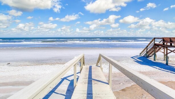A wooden boardwalk leading to a beach with a wooden structure on the right.