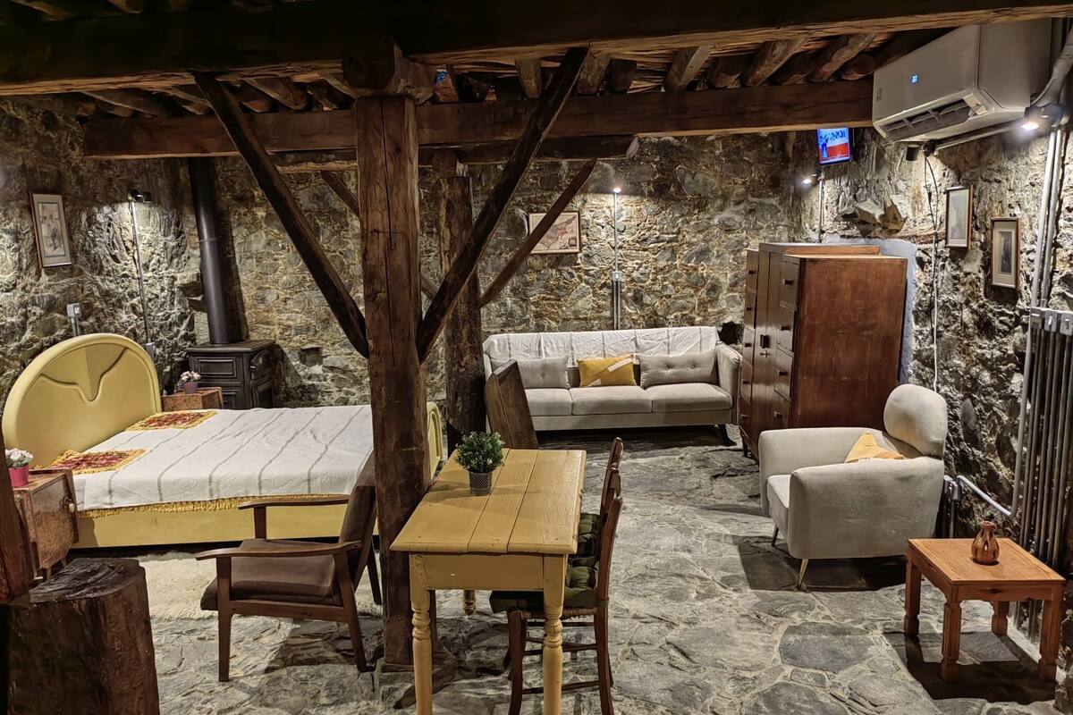 A rustic room with a bed, a sofa, a table, and a cabinet.