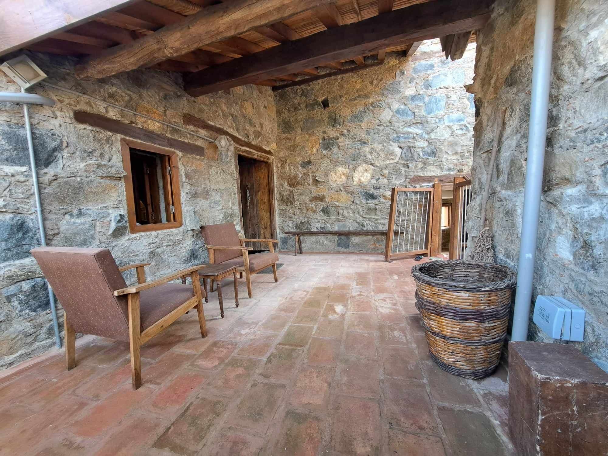 Una habitación con paredes de piedra, suelo de baldosas, muebles de madera y una cesta tejida.