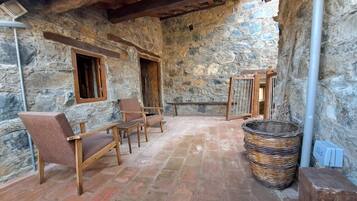 A stone-walled room with a tiled floor, wooden furniture, and a woven basket.