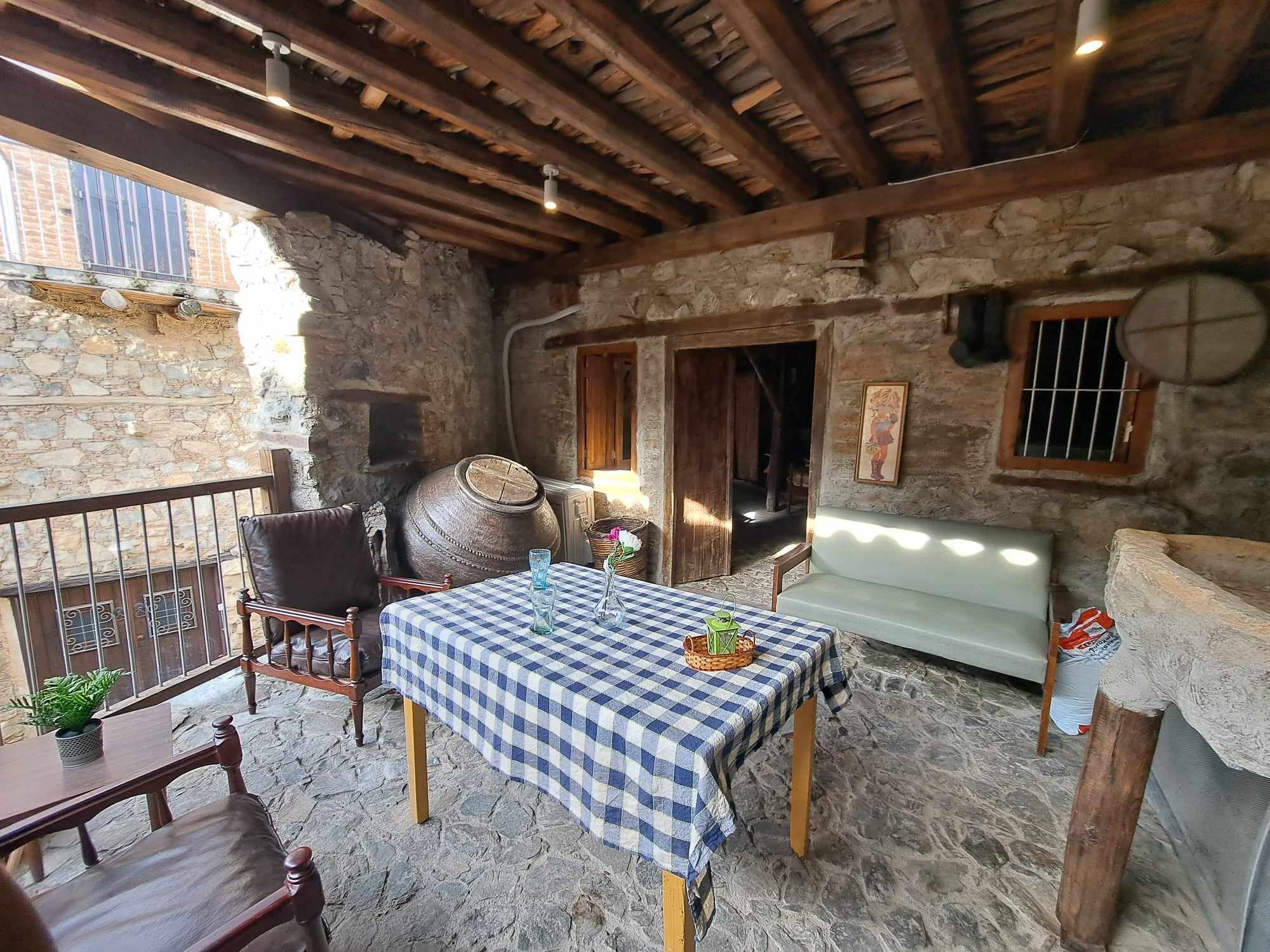 A rustic stone interior with a checkered tablecloth, wooden furniture, and a stone barrel.