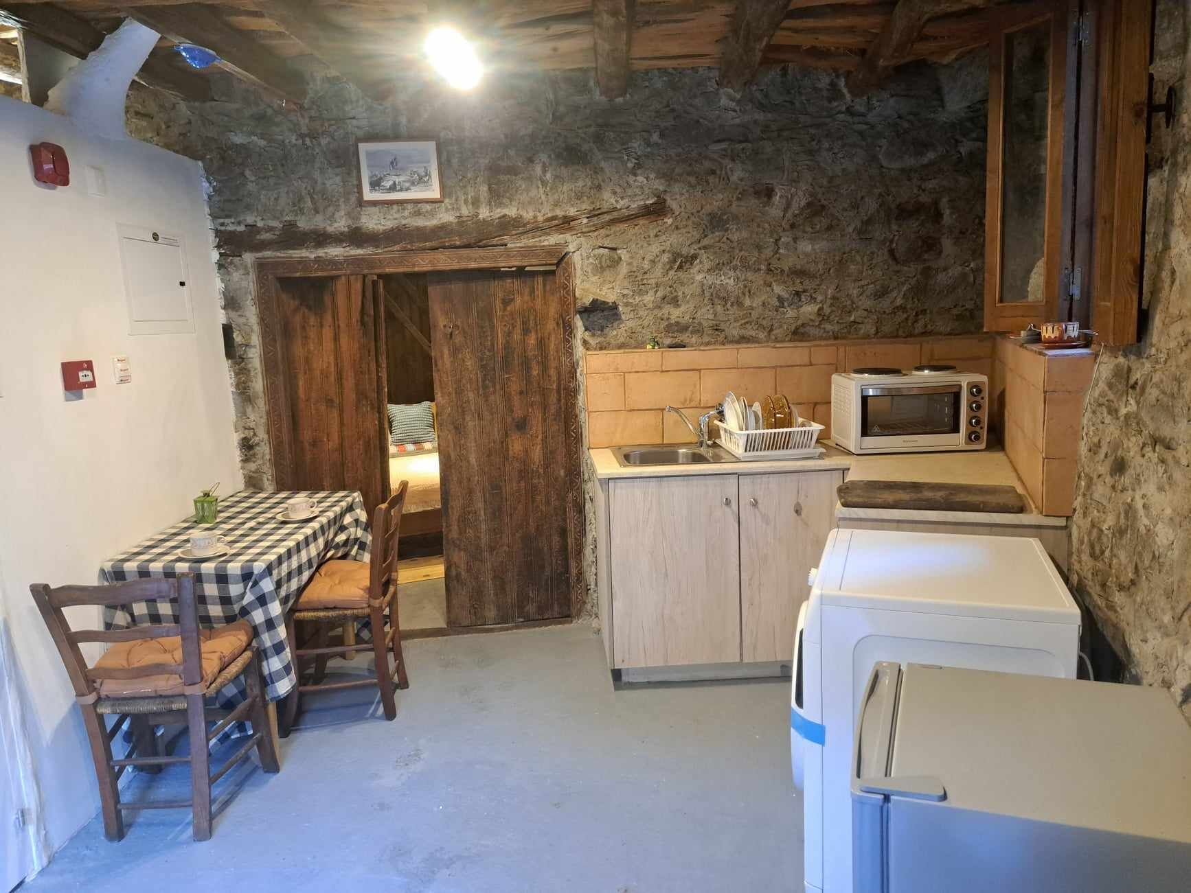 A rustic kitchen with a checkered table, wooden cabinets, a microwave, and a refrigerator.