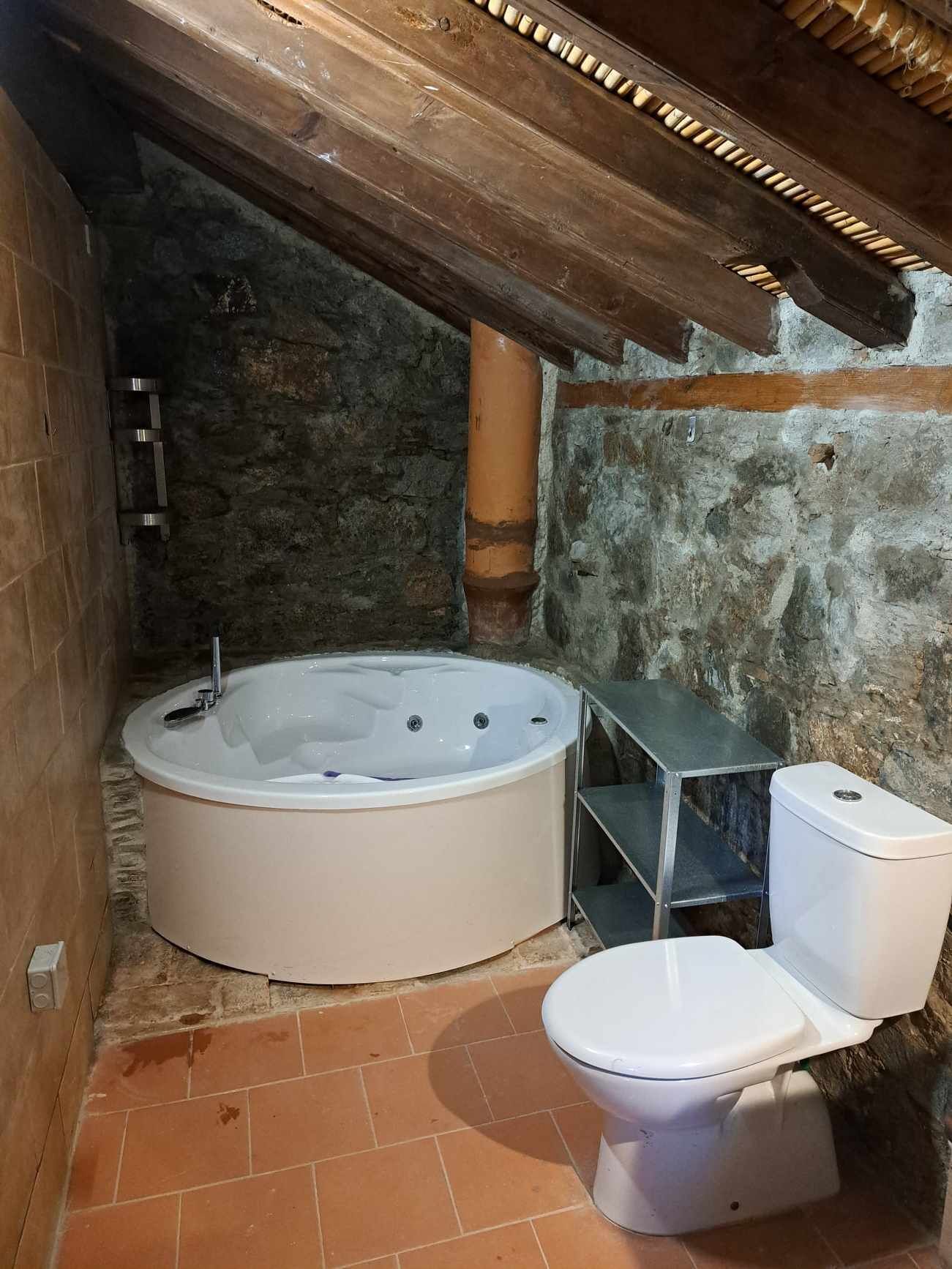 Un bagno con vasca, water e un piccolo ripiano.