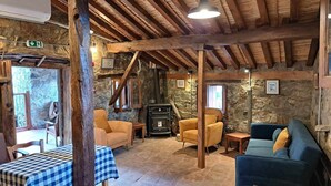 A rustic interior with stone walls, wooden beams, a fireplace, and seating areas. - PITHARIA (Askas)