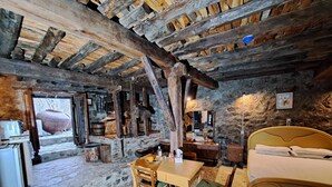 A rustic room with a stone floor, wooden furniture, a bed, and a stone wall. - PITHARIA (Askas)