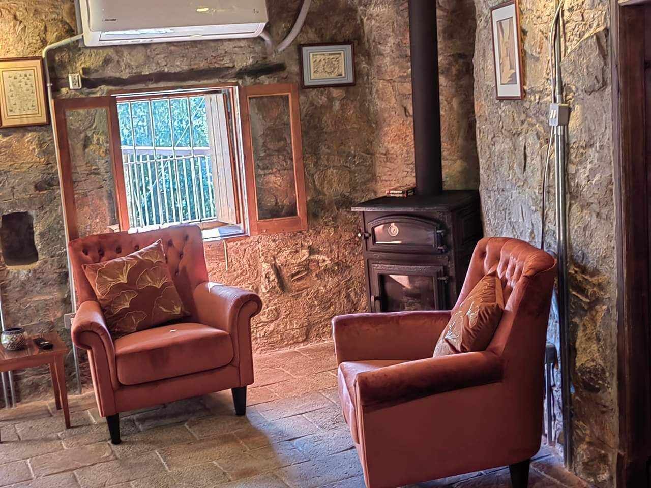 A cozy room with stone walls, a fireplace, and two leather armchairs.