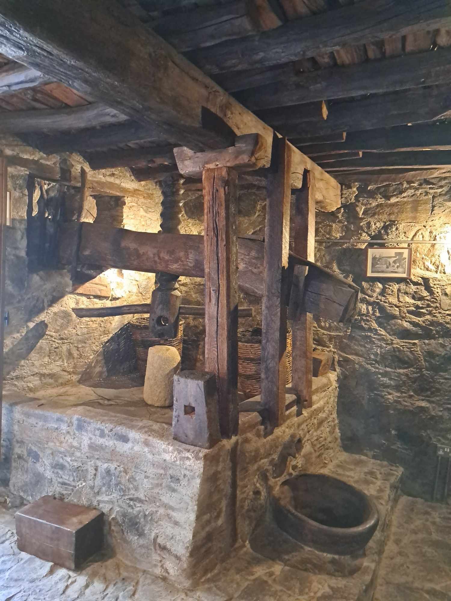 Una habitación rústica con paredes de piedra, un banco de piedra, vigas de madera y una lámpara colgante.