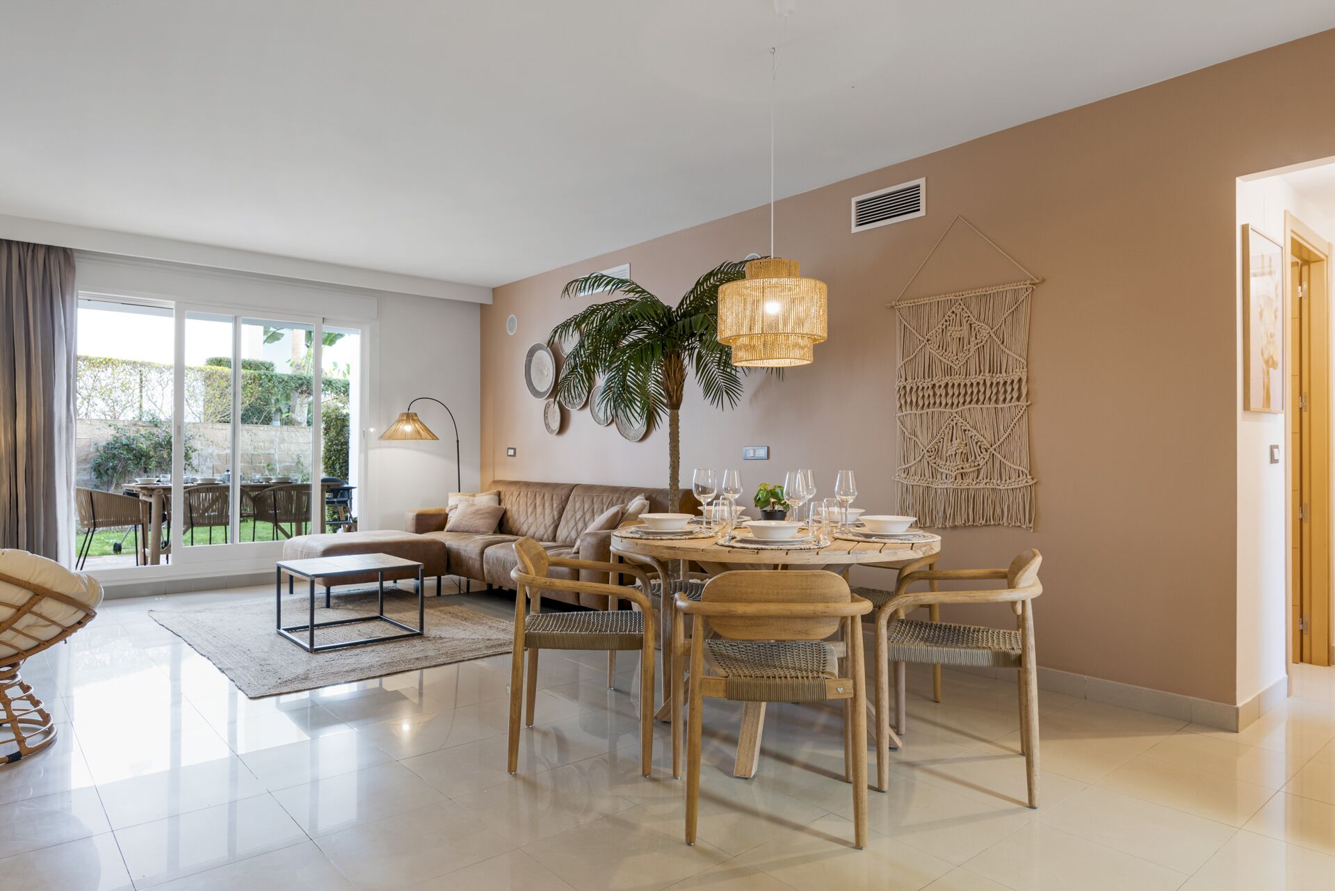 A modern living room with a dining area, large windows, and a potted plant.