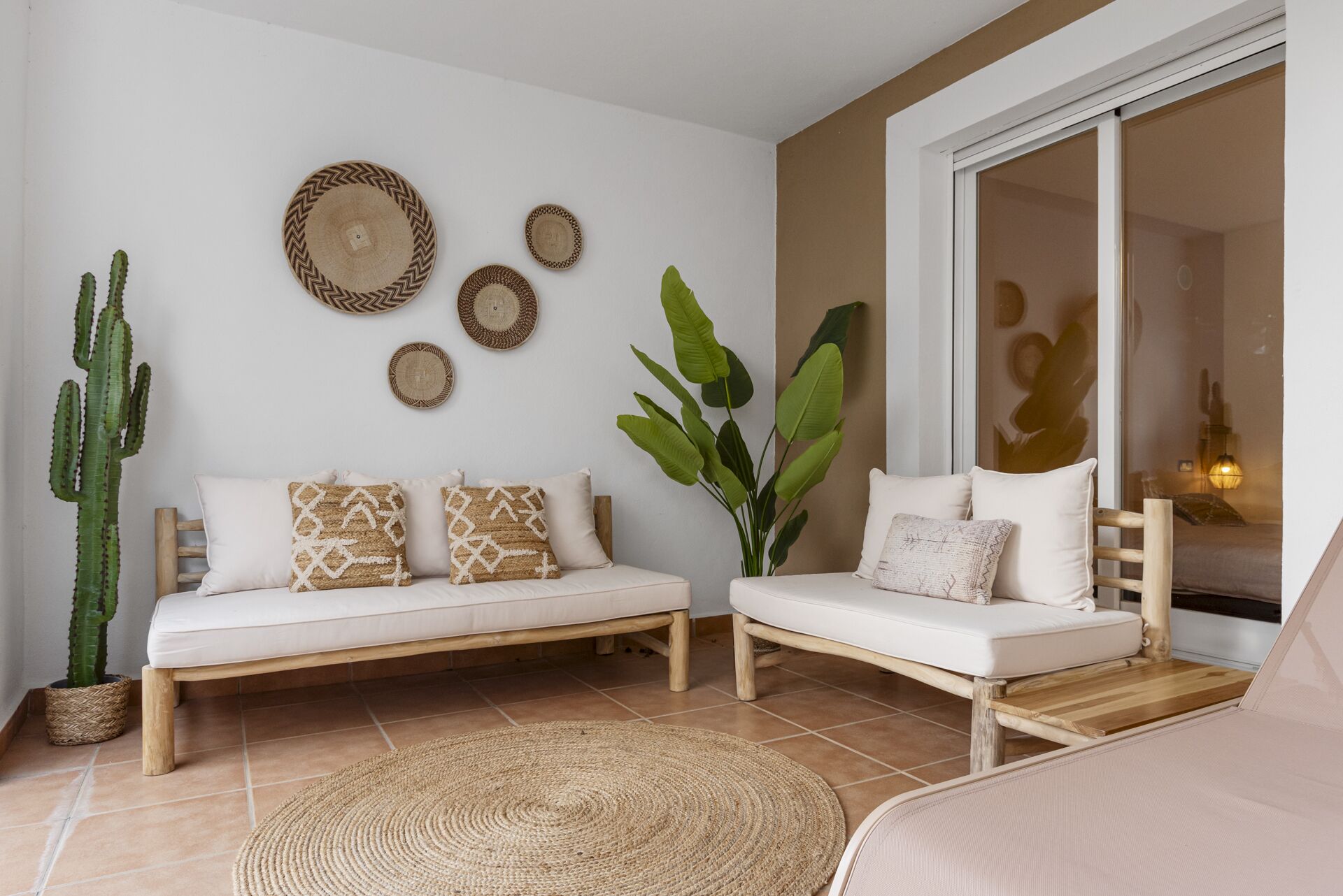 A living room with a sofa set, a large cactus, and decorative woven items on the wall.