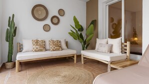 A living room with a sofa set, a large cactus, and decorative woven items on the wall. - Casa Livia with Auping beds (Estepona)