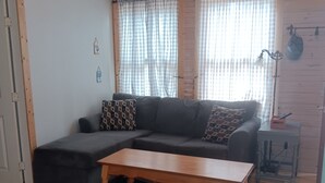Un salon avec un canapé d’angle, une table basse en bois et un tapis à motifs.