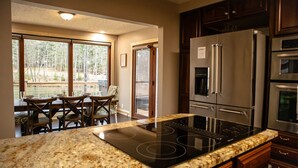 Una cocina con encimera de granito, electrodomésticos de acero inoxidable y una zona de comedor con mesa y sillas.