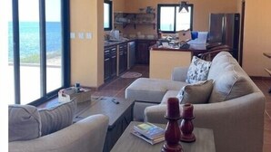 Un salon avec un canapé, une table basse et une vue sur l’océan.