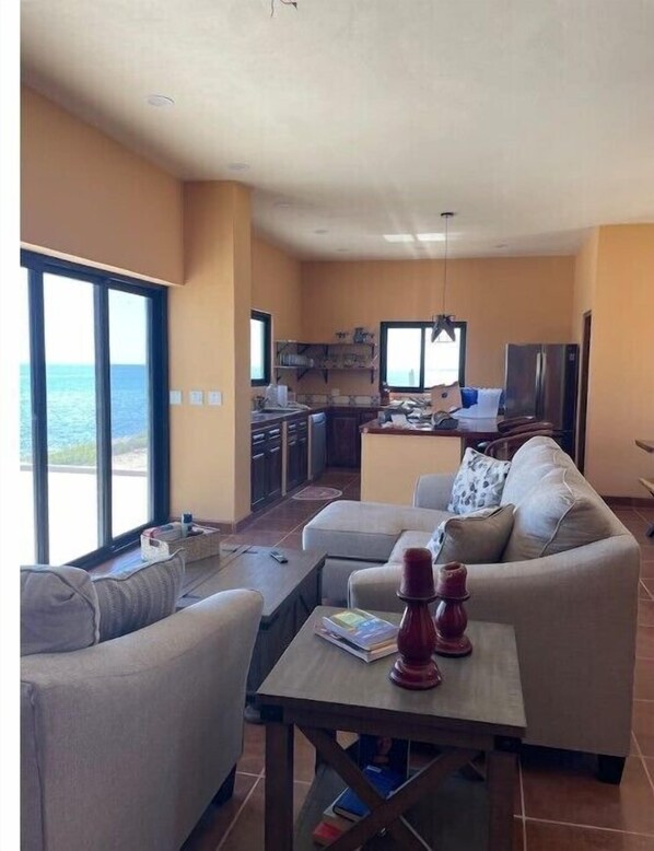 A living room with a sofa, a coffee table, and a view of the ocean. - Beachfront paradise
(El Cardonal)