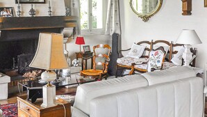 Una habitación tradicional con chimenea, una cama con dosel, una silla de madera y un espejo en la pared.