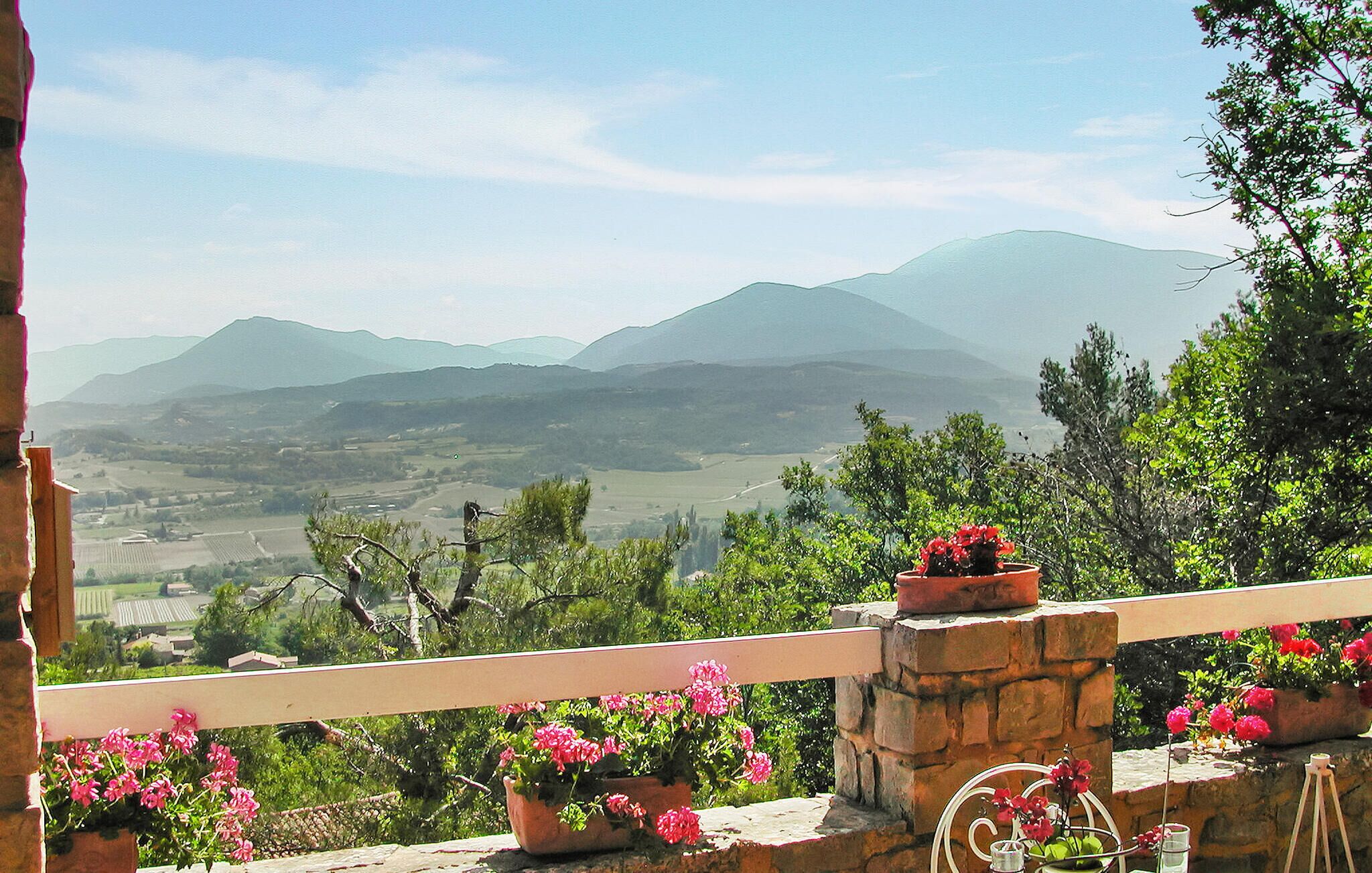 A balcony with potted plants and a view of distant mountains.