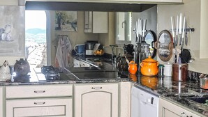 Cocina con estufa, pileta y diversos utensilios. Se observa una ventana con vistas al paisaje.