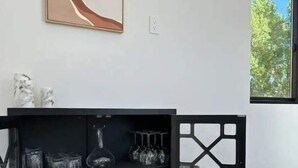Une pièce moderne avec une console noire, une grande peinture abstraite et une fenêtre donnant sur des arbres.