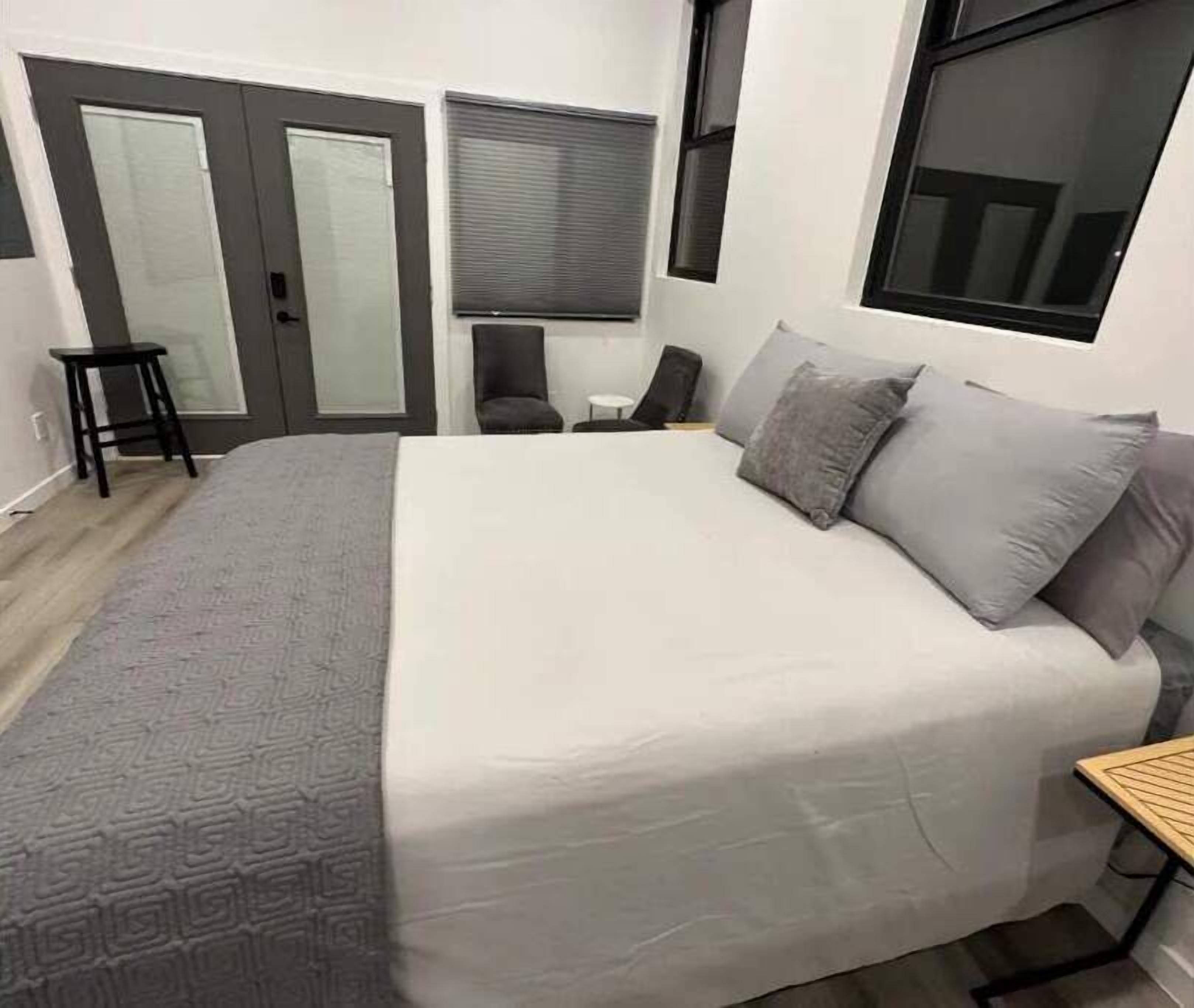 Camera da letto con un letto grande, due porte, una finestra, un tavolino e una sedia.