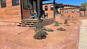 Une cabane moderne en bois, dotée d’un porche couvert et d’un petit jardin.