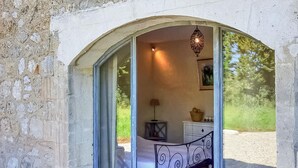 Une pièce avec un mur en pierre, un lit avec une tête de lit en métal, une lampe et un luminaire suspendu.