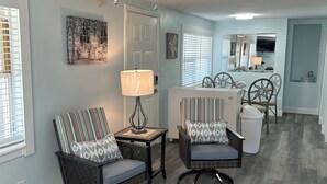 A living room with two wicker chairs, a small table with a lamp, and a ceiling fan. - Crescent Beach Retreat - Steps to Sand - Pet Friendly (St. Augustine)