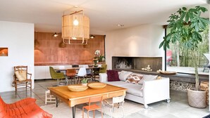 A modern living room with a wooden dining table, a sofa, and a fireplace.