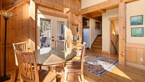 A wooden interior with a round dining table, chairs, a rug, and a staircase. - Mountain Retreat, Sunset Views, and 20 Minutes to Asheville! (Swannanoa)