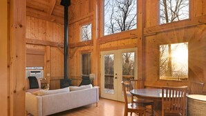 A cozy cabin interior with a sofa, dining table, chairs, and a fireplace. - Mountain Retreat, Sunset Views, and 20 Minutes to Asheville! (Swannanoa)