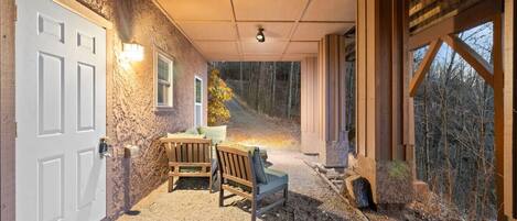 Un espacio al aire libre techado con piso de grava, bancos de madera y una puerta.