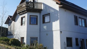 Un edificio di due piani con un balcone al secondo piano, diverse finestre e una porta ben visibile.